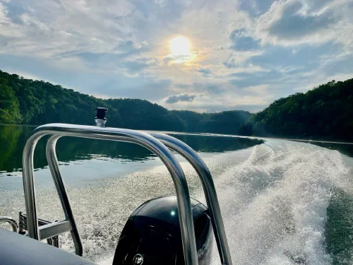 Motorboat cutting across the lake with foamy wake and forested ridges