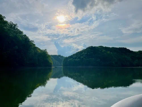 Late-day sunbeams breaking through clouds over calm lake water